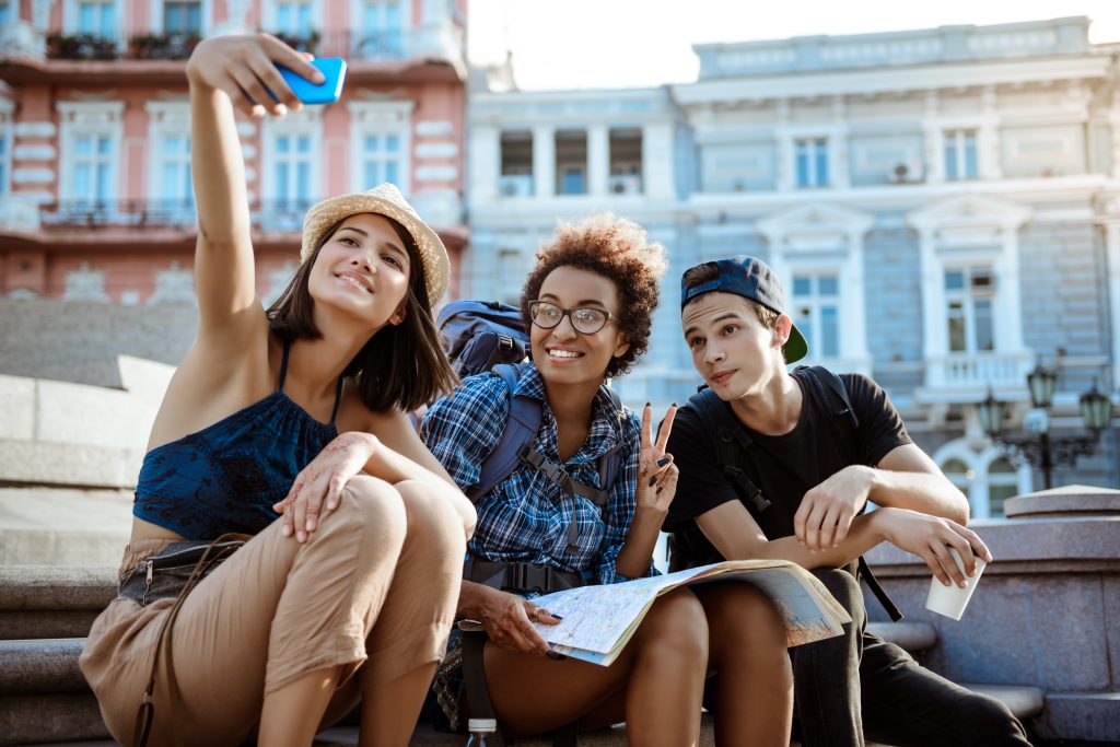 riends-travelers-with-backpacks-smiling-making-selfie-sitting-near-sight